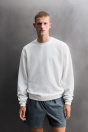 Zara ВАФЕЛЬНАЯ ТРЕНИРОВОЧНАЯ ТОЛСТОВКА С КРУГЛЫМ ВЫРЕЗОМ белого цвета.